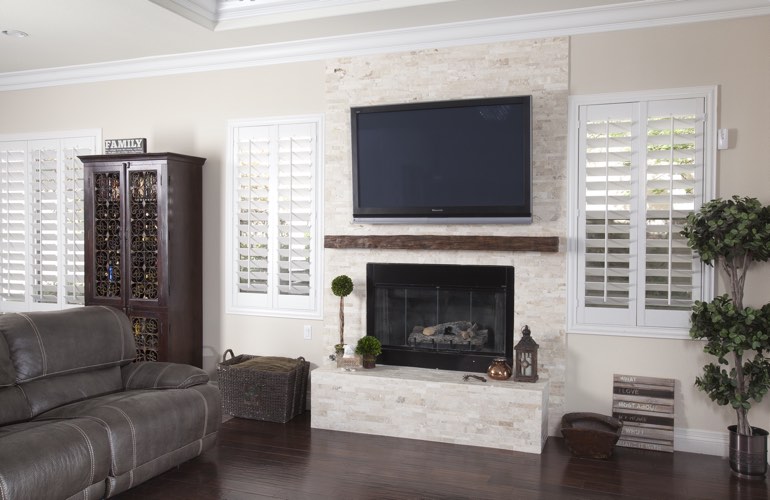 White plantation shutters in a Honolulu living room with plank hardwood floors.